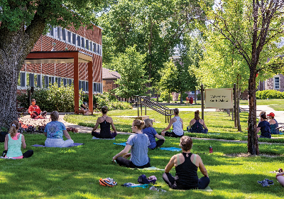 Health sciences students doing yoga outside on the MUC lawn.