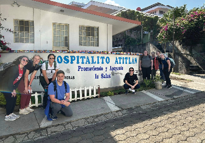 OT and PT students in Guatamala posing for a photo in front of a sign.