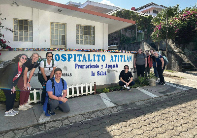 OT and PT students in Guatamala posing for a photo in front of a sign.