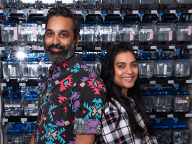 Yohaan and Mindy Fernandes posing in front of lab shelves