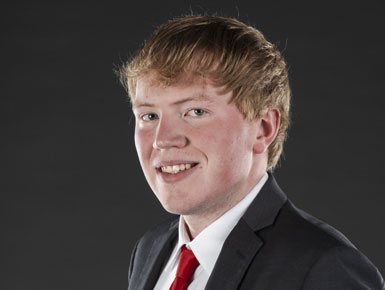 Taylor Van Emmerick wearing a suit in a studio.