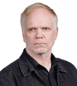 duncan barlow sits for his professional photo. He is wearing a black shirt and looking at the camera.
