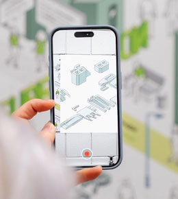 Young Ae Kim, Ph.D., holds up a phone that is in the midst of taking a photo or video recording of 3D blueprints.