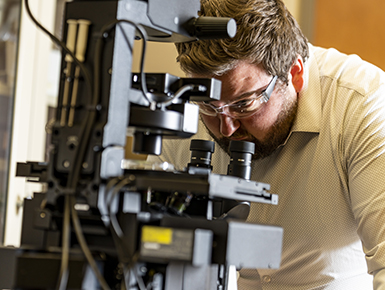 Student studies under a microscope in a trac lab 