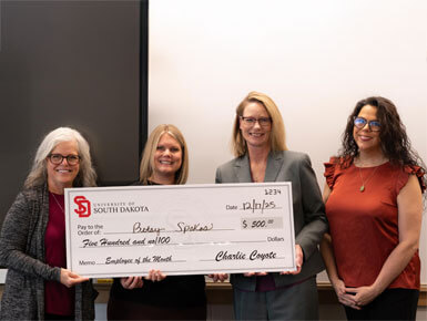 Betsy Spokas is presented with a giant check for her CSA service. Three other people are pictured with her, including USD President Sheila K. Gestring.