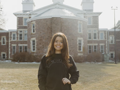 Ellie Hart stands in front of Old Main on USD's campus.