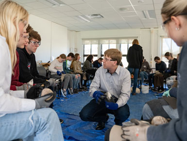 Professor Tony Krus demonstrates flint knapping in class