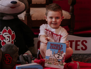 A child holding the book Where's Charlie