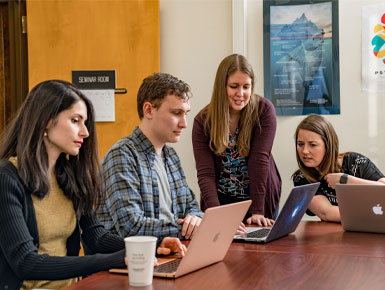 Four students sitting at desk with computers