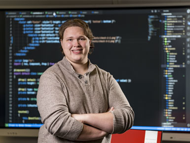 Adam Grady is in the USD computer lab smiling at the camera