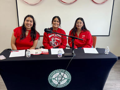 Female members of the SDHCC sit at a table, which has a black tablecloth with the SDHCC logo.