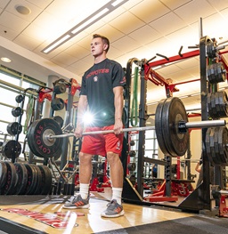 Male student lifting weights at the Wellness Center