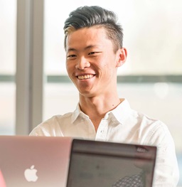 Student Smiling While Working on a Laptop