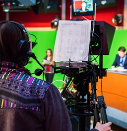 Student wearing headphones and running camera for student news.