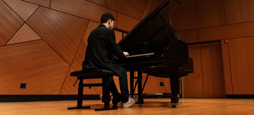 A USD Student playing piano on stage.