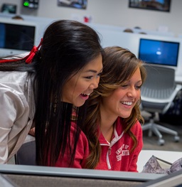 Graduate assistant works with student in the computer lab
