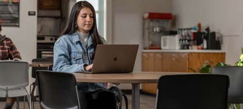 Female student working on laptop at a desk