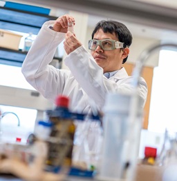 Male in White Lab Coat and Goggles in a Research Lab